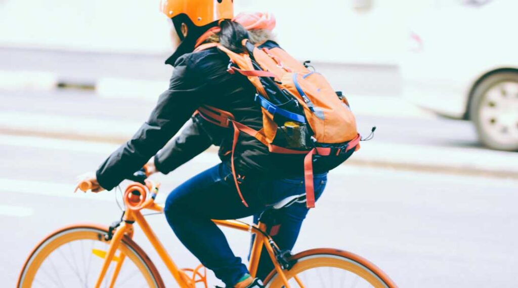 ragazza in bicicletta con zaino con stampa riflettente