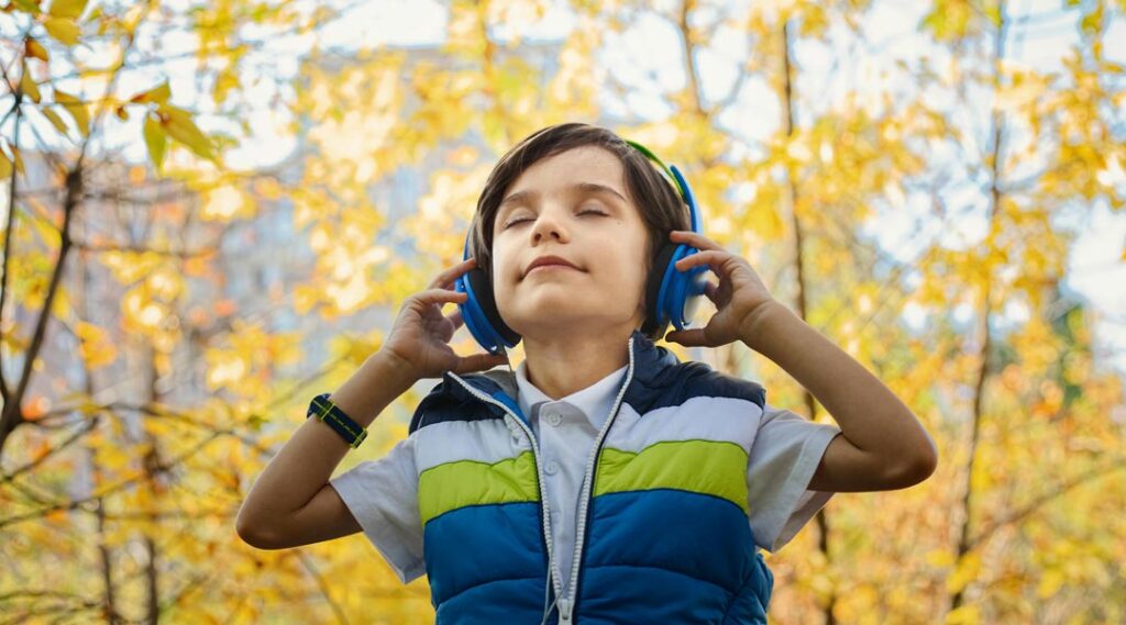 bambino con le cuffie in mezzo al parco